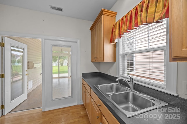 301 Garner Dr, Salisbury, NC 28146 - kitchen with a sink, dark countertops, light wood finished floors, and brown cabinetry