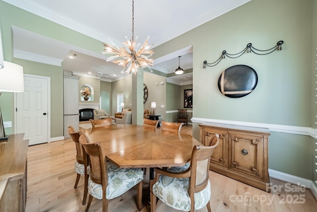 12039 Lawings Corner Dr, Huntersville, NC 28078 - dining area with a chandelier, crown molding, light wood-style flooring, recessed lighting, and a glass covered fireplace