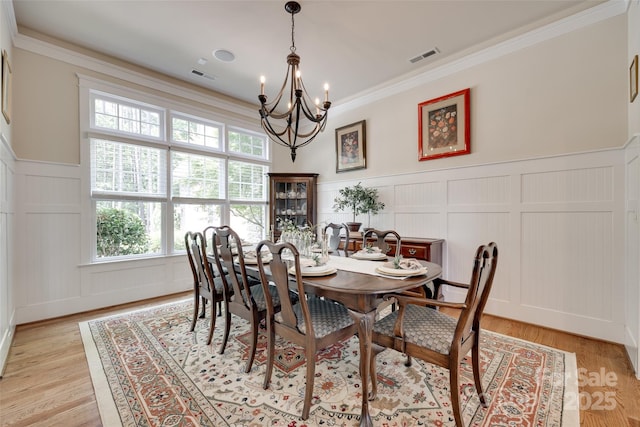18311 Rosapenny Rd, Charlotte, NC 28278 - dining area with a decorative wall, a chandelier, a wainscoted wall, crown molding, and light wood finished floors