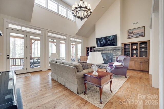 18311 Rosapenny Rd, Charlotte, NC 28278 - living room featuring a high ceiling, light wood-style floors, a chandelier, and a stone fireplace