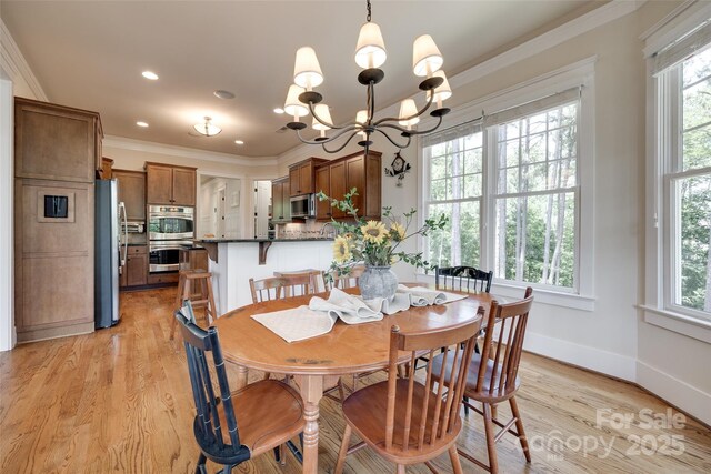 18311 Rosapenny Rd, Charlotte, NC 28278 - dining space with healthy amount of natural light, ornamental molding, baseboards, light wood-style flooring, and a chandelier