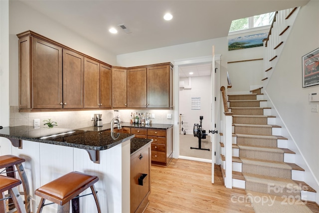 18311 Rosapenny Rd, Charlotte, NC 28278 - kitchen with light wood-type flooring, a peninsula, a breakfast bar, recessed lighting, and brown cabinetry