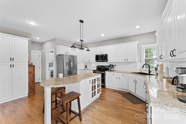 230 Fairway Falls Rd, Mills River, NC 28759 - kitchen with black range with electric stovetop, a sink, stainless steel refrigerator with ice dispenser, a breakfast bar, and washer / dryer