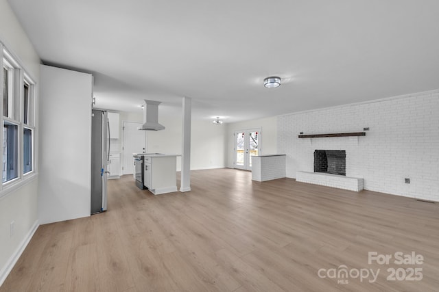 276 Bob Mcneill Rd, West Jefferson, NC 28694 - unfurnished living room with light wood finished floors, a brick fireplace, baseboards, and brick wall