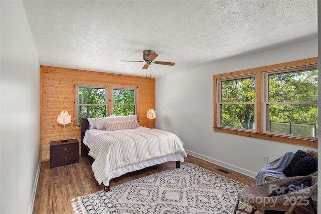 225 Ford Rd, Waynesville, NC 28786 - bedroom with baseboards, wooden walls, a textured ceiling, wood finished floors, and ceiling fan