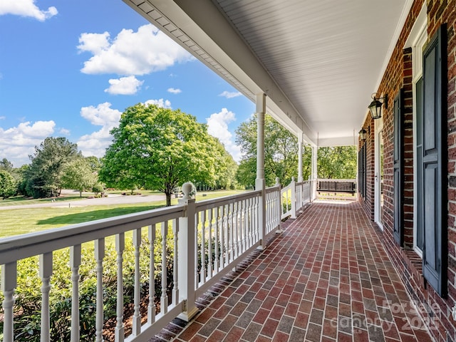 balcony featuring covered porch and view of wooded area