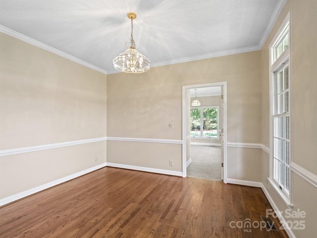 spare room with a chandelier, wood finished floors, baseboards, and ornamental molding