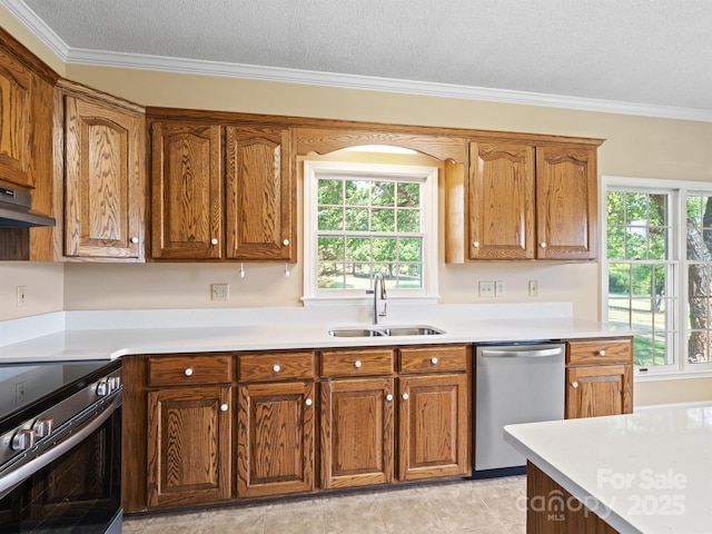 kitchen featuring stainless steel appliances, a sink, plenty of natural light, light countertops, and crown molding