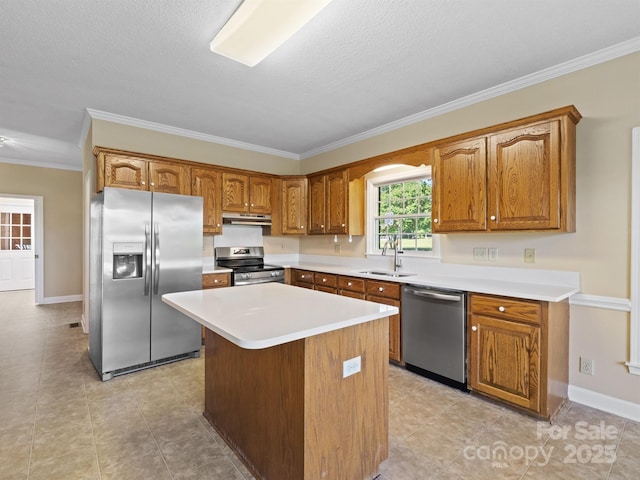 kitchen featuring appliances with stainless steel finishes, under cabinet range hood, a sink, ornamental molding, and brown cabinets