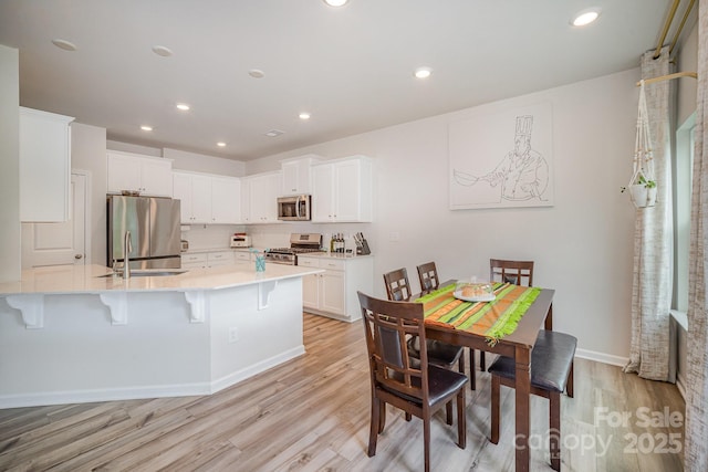 18026 Stark Way, Charlotte, NC 28278 - kitchen with stainless steel appliances, a peninsula, a kitchen breakfast bar, light wood finished floors, and light countertops