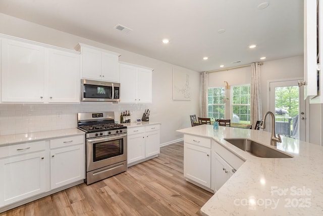 18026 Stark Way, Charlotte, NC 28278 - kitchen with stainless steel appliances, a sink, tasteful backsplash, light wood finished floors, and white cabinets