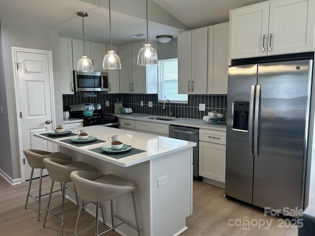 1004 Johnson St, Charlotte, NC 28206 - kitchen featuring appliances with stainless steel finishes, a sink, tasteful backsplash, light wood-style flooring, and a kitchen island