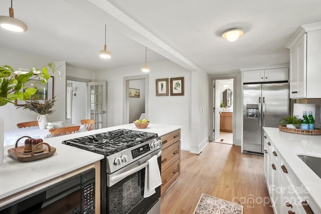 1000 Oakshade Ave, Kannapolis, NC 28083 - kitchen featuring appliances with stainless steel finishes, light countertops, white cabinetry, light wood finished floors, and decorative light fixtures