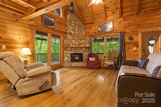 108 Cougar Aly Unit 79, Lake Lure, NC 28746 - living room with wooden ceiling with exposed beams, wood walls, healthy amount of natural light, light wood-style flooring, and a stone fireplace