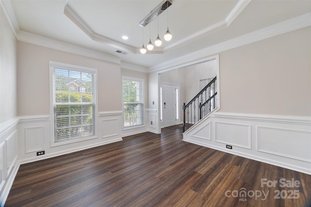 entryway featuring dark wood-type flooring, stairs, a tray ceiling, a decorative wall, and ornamental molding