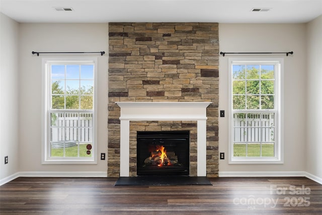 unfurnished living room with wood finished floors, a stone fireplace, and baseboards