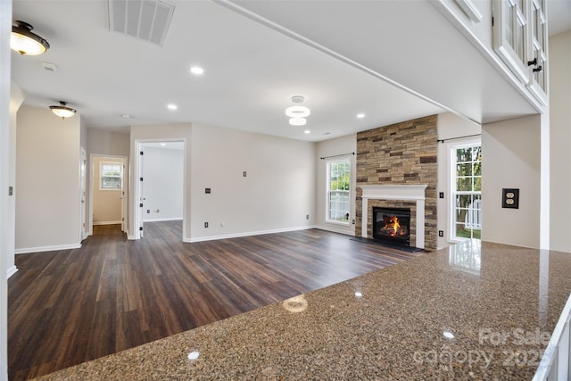 unfurnished living room with dark wood-style flooring, a fireplace, baseboards, and recessed lighting