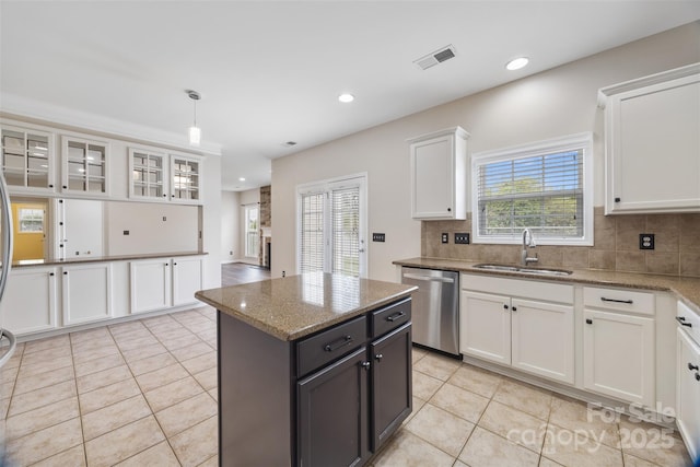 kitchen featuring stainless steel dishwasher, a sink, white cabinetry, light tile patterned floors, and decorative backsplash