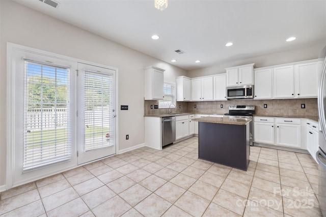 kitchen featuring appliances with stainless steel finishes, tasteful backsplash, a center island, light tile patterned flooring, and recessed lighting