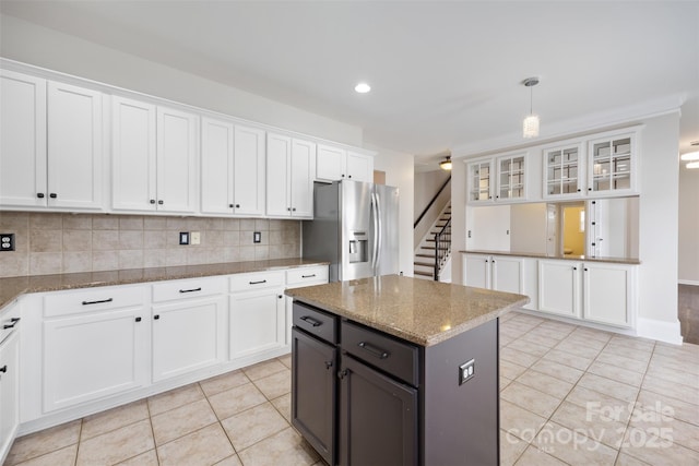 kitchen with stainless steel fridge with ice dispenser, white cabinetry, light tile patterned floors, decorative backsplash, and glass insert cabinets