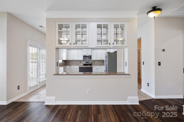kitchen featuring appliances with stainless steel finishes, wood finished floors, baseboards, white cabinets, and glass insert cabinets