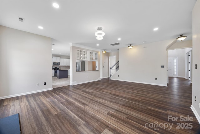 unfurnished living room with dark wood-style flooring, stairway, baseboards, and recessed lighting