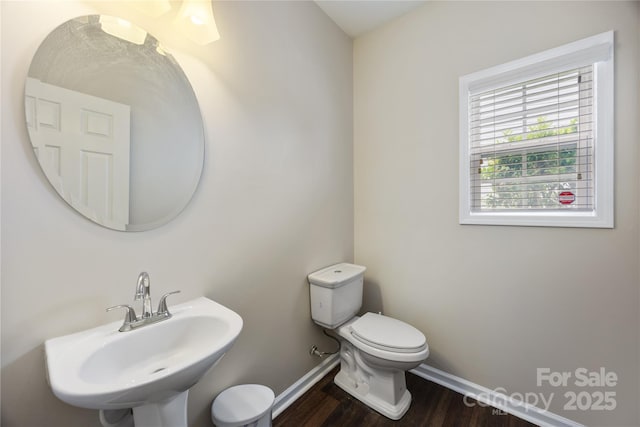 bathroom with a sink, toilet, wood finished floors, and baseboards