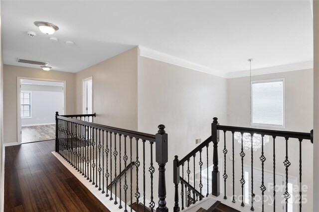 hallway with an upstairs landing, dark wood-style flooring, baseboards, and crown molding