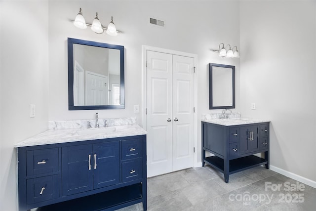 full bath featuring two vanities, baseboards, and a closet