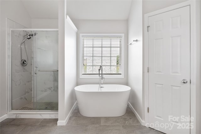 bathroom with baseboards, a shower stall, and a freestanding bath