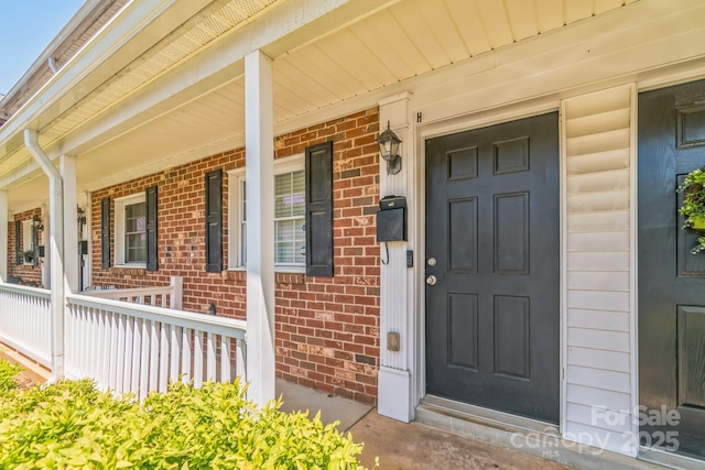 property entrance featuring brick siding and a porch