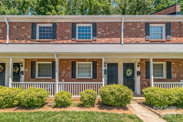 view of property with covered porch and brick siding