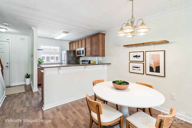 dining room featuring a chandelier, dark wood-type flooring, crown molding, and baseboards