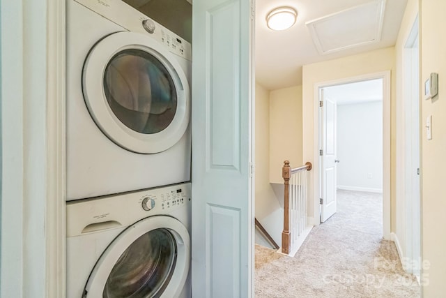 laundry area with stacked washer / drying machine, carpet flooring, attic access, and baseboards