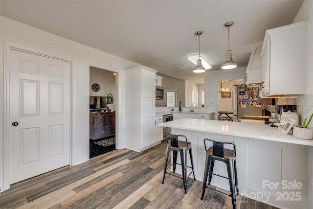 1140 Landsdown Dr, Salisbury, NC 28147 - kitchen with a peninsula, appliances with stainless steel finishes, white cabinetry, dark wood-style flooring, and a sink