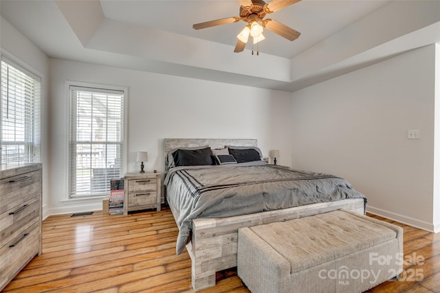 1140 Landsdown Dr, Salisbury, NC 28147 - bedroom featuring a tray ceiling, baseboards, light wood finished floors, and a ceiling fan