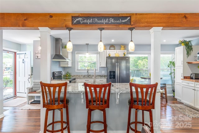 307 Tree Haven Blvd, Hendersonville, NC 28791 - kitchen featuring stainless steel appliances, wall chimney range hood, wood finished floors, white cabinets, and light stone countertops