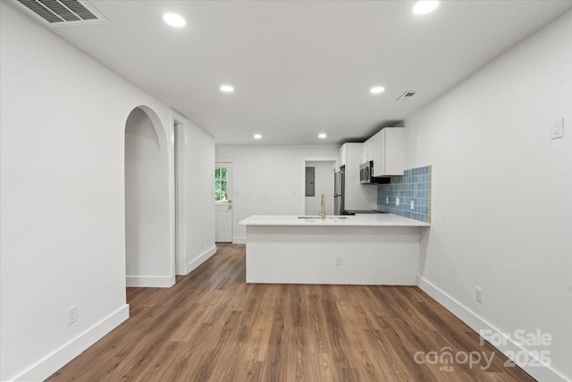 kitchen featuring a sink, stainless steel appliances, a peninsula, light countertops, and white cabinets