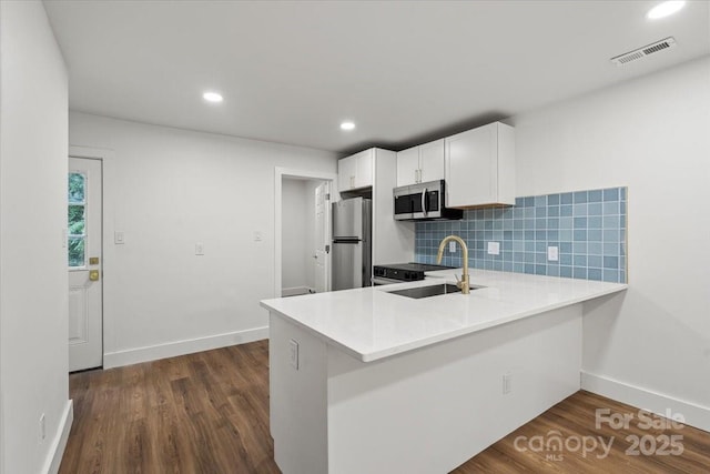 kitchen with stainless steel appliances, a sink, tasteful backsplash, light countertops, and white cabinetry