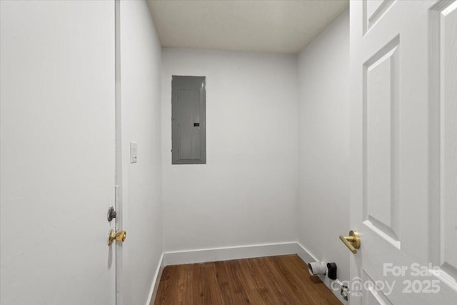 laundry area featuring electric panel, dark wood-type flooring, and baseboards