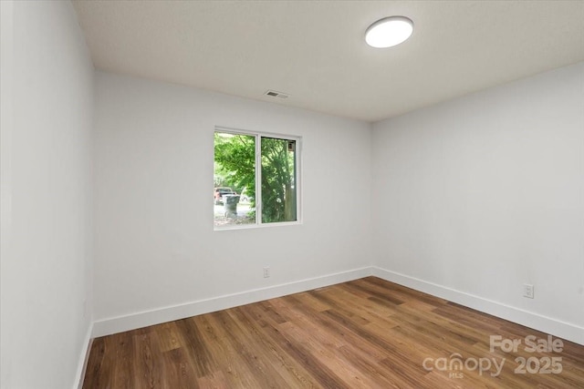 spare room with baseboards and wood finished floors