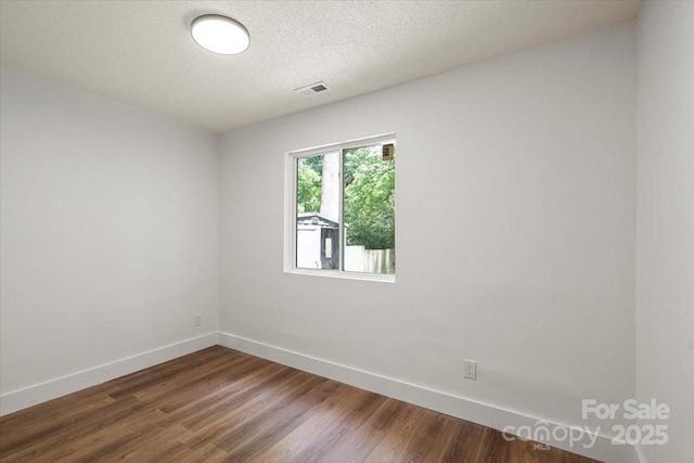 empty room with baseboards, dark wood-style flooring, and a textured ceiling