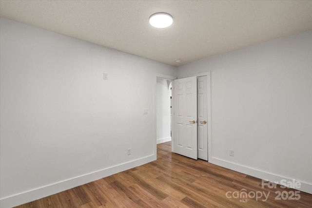 spare room featuring baseboards and wood finished floors