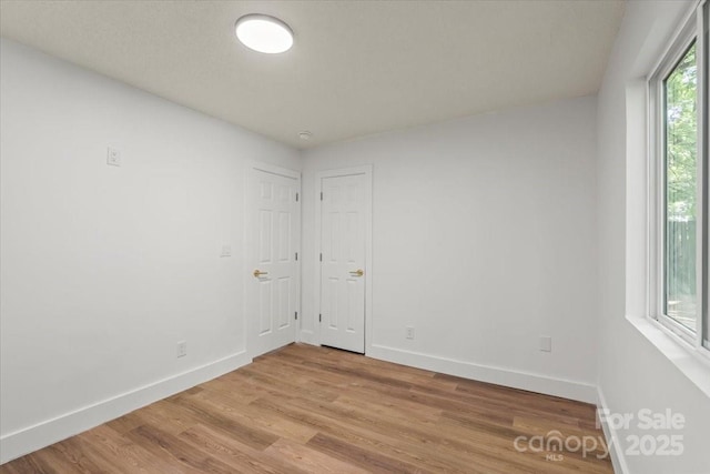 spare room with baseboards and light wood-type flooring