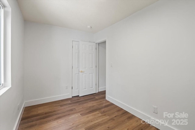 spare room featuring baseboards and wood finished floors