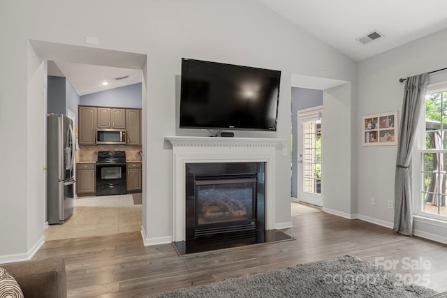 3820 Leela Palace Way, Fort Mill, SC 29708 - living room featuring vaulted ceiling, light wood finished floors, baseboards, a glass covered fireplace, and recessed lighting
