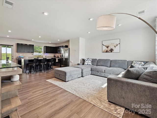 living area featuring light wood-type flooring and recessed lighting