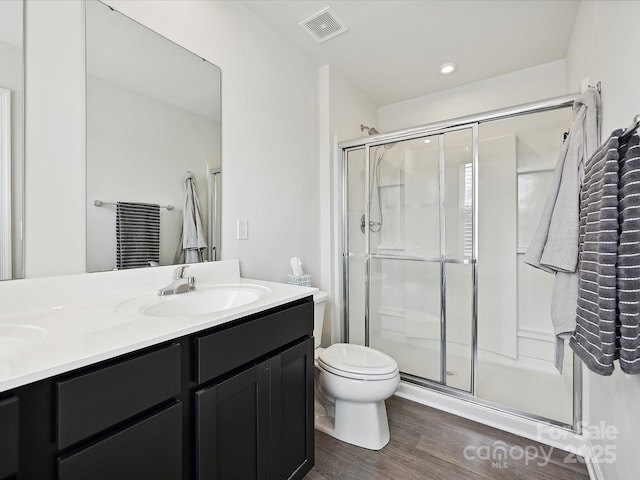 full bath featuring a stall shower, wood finished floors, vanity, and toilet