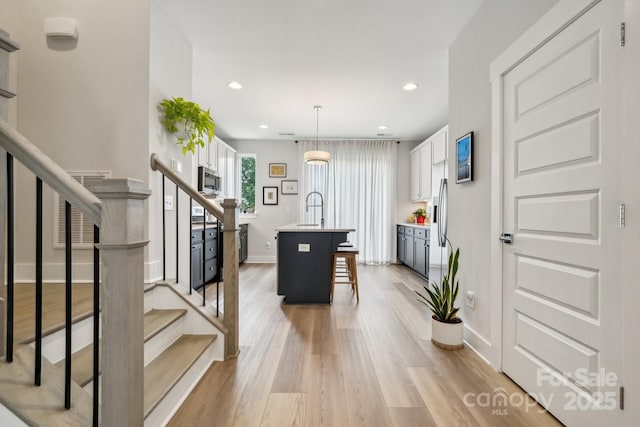 entryway featuring baseboards, stairs, light wood-style floors, and recessed lighting