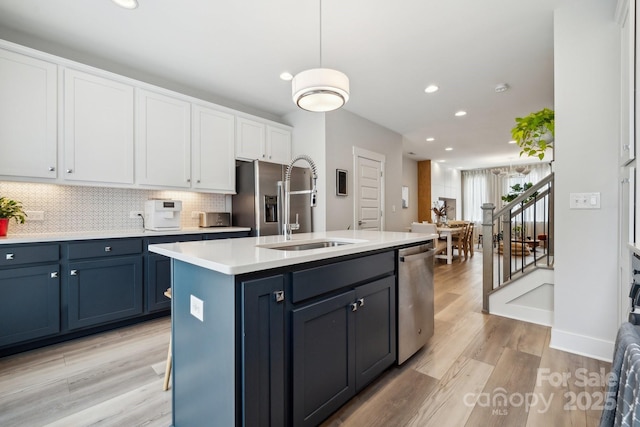 kitchen featuring stainless steel appliances, a sink, white cabinetry, recessed lighting, and backsplash